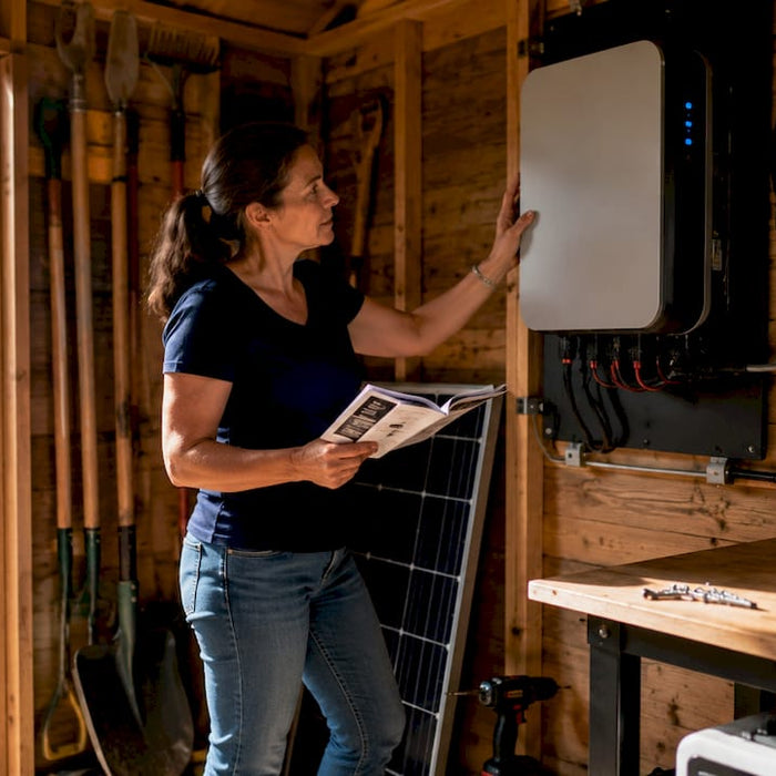 Woman installing solar battery in home garage