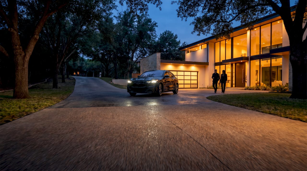 Car arriving at a modern house with illuminated windows